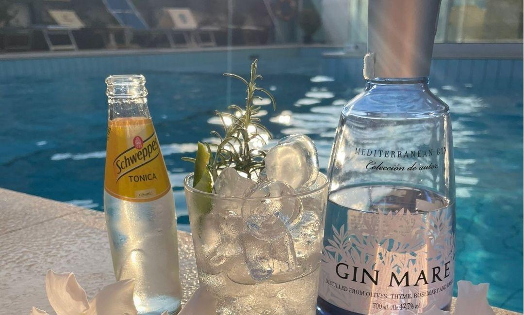 Cocktail di gin e tonica a bordo piscina con ghiaccio e rosmarino.